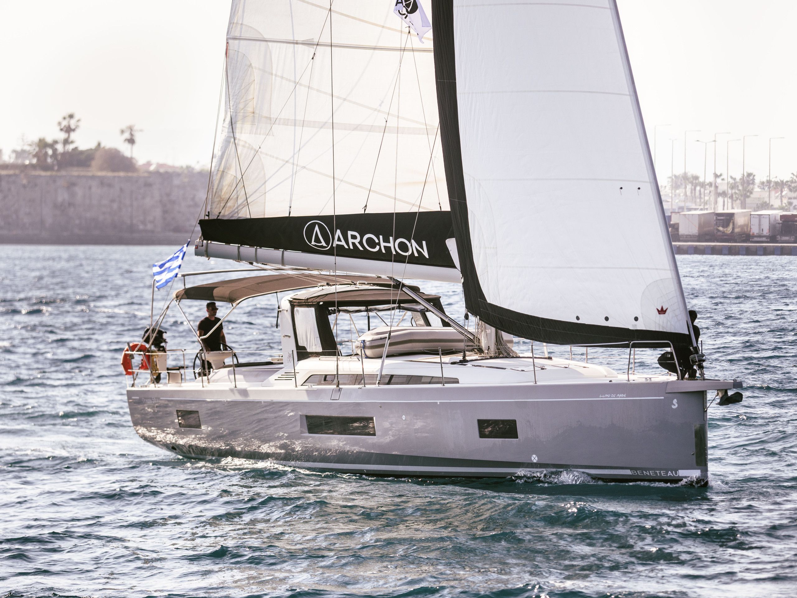 A sailboat with a name 'ARCHON' on its sail, equipped with a cabin and a deck area.