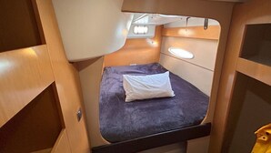A compact, well-lit interior with a single bed, a small window, and wooden paneling. - Sun-Kissed Sailing Adventure in Gran Barrera de Coral from Playa Airlie, Queensland (Airlie Beach)