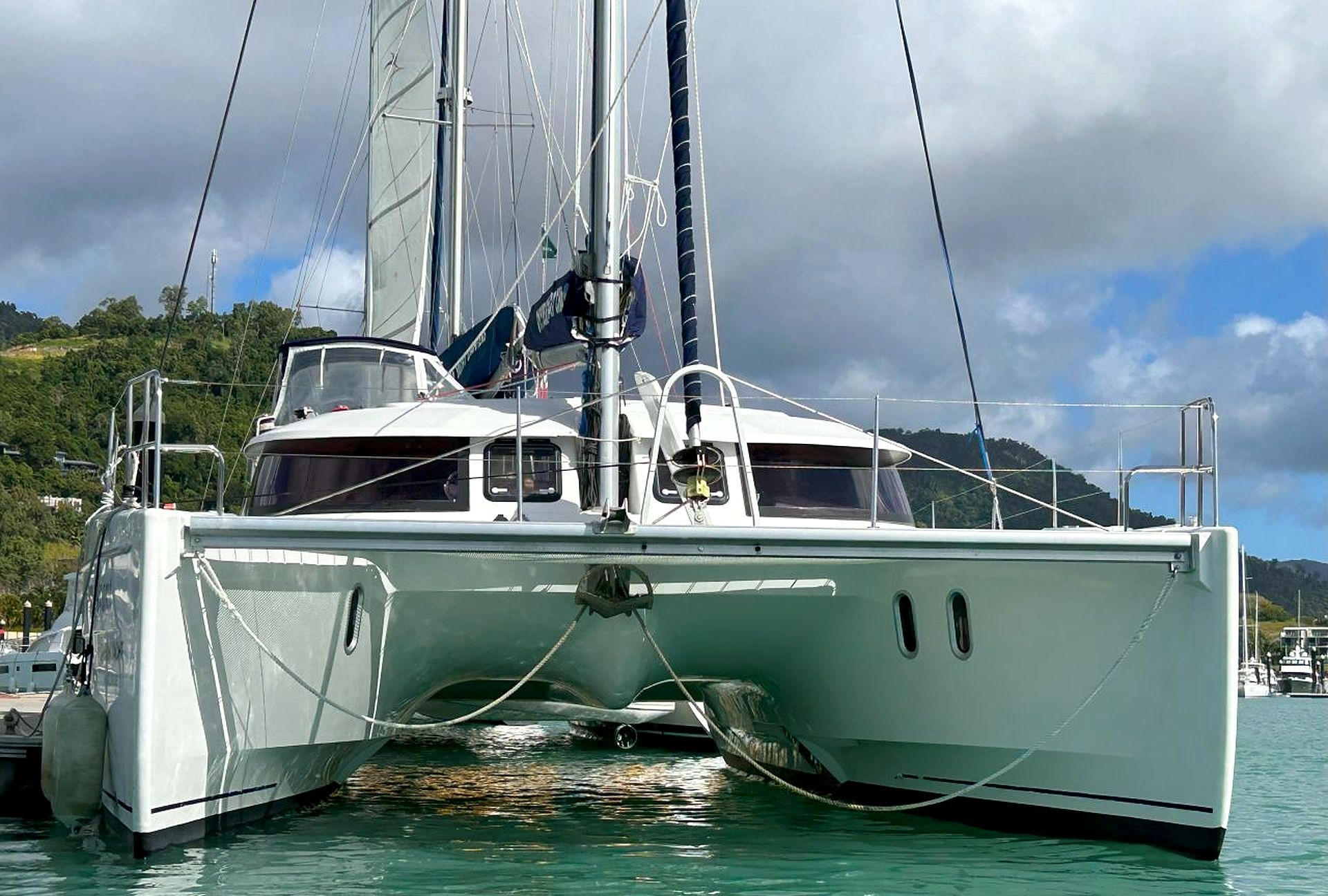 A sailboat docked at a marina with a view of a mountainous landscape in the background.