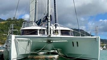 A sailboat docked at a marina with a view of a mountainous landscape in the background.
