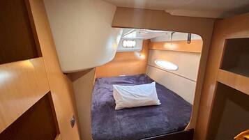 A compact, well-lit interior with a single bed, a small window, and a bench.