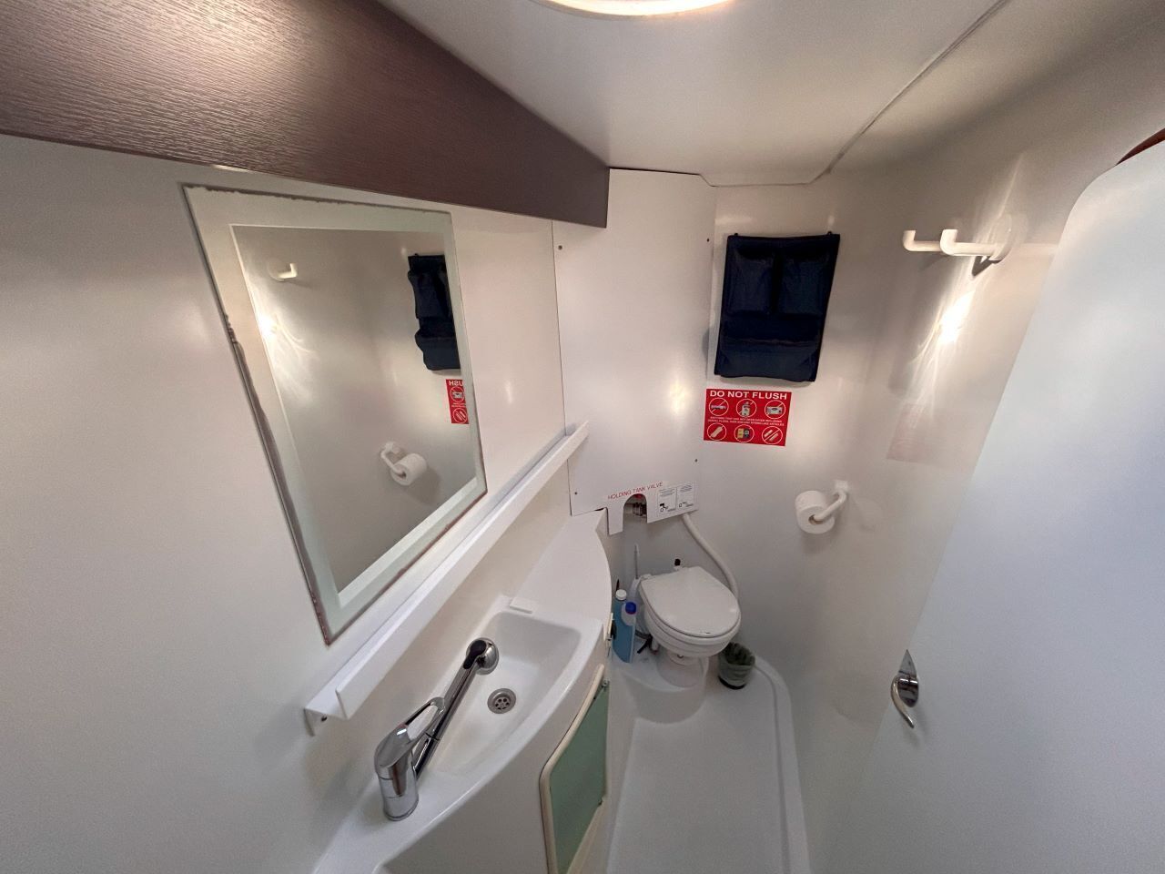 A compact bathroom with a sink, toilet, and mirror.