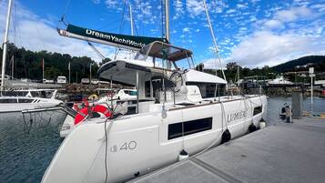 A white yacht docked at a marina with a 'Dream Yacht World' banner.