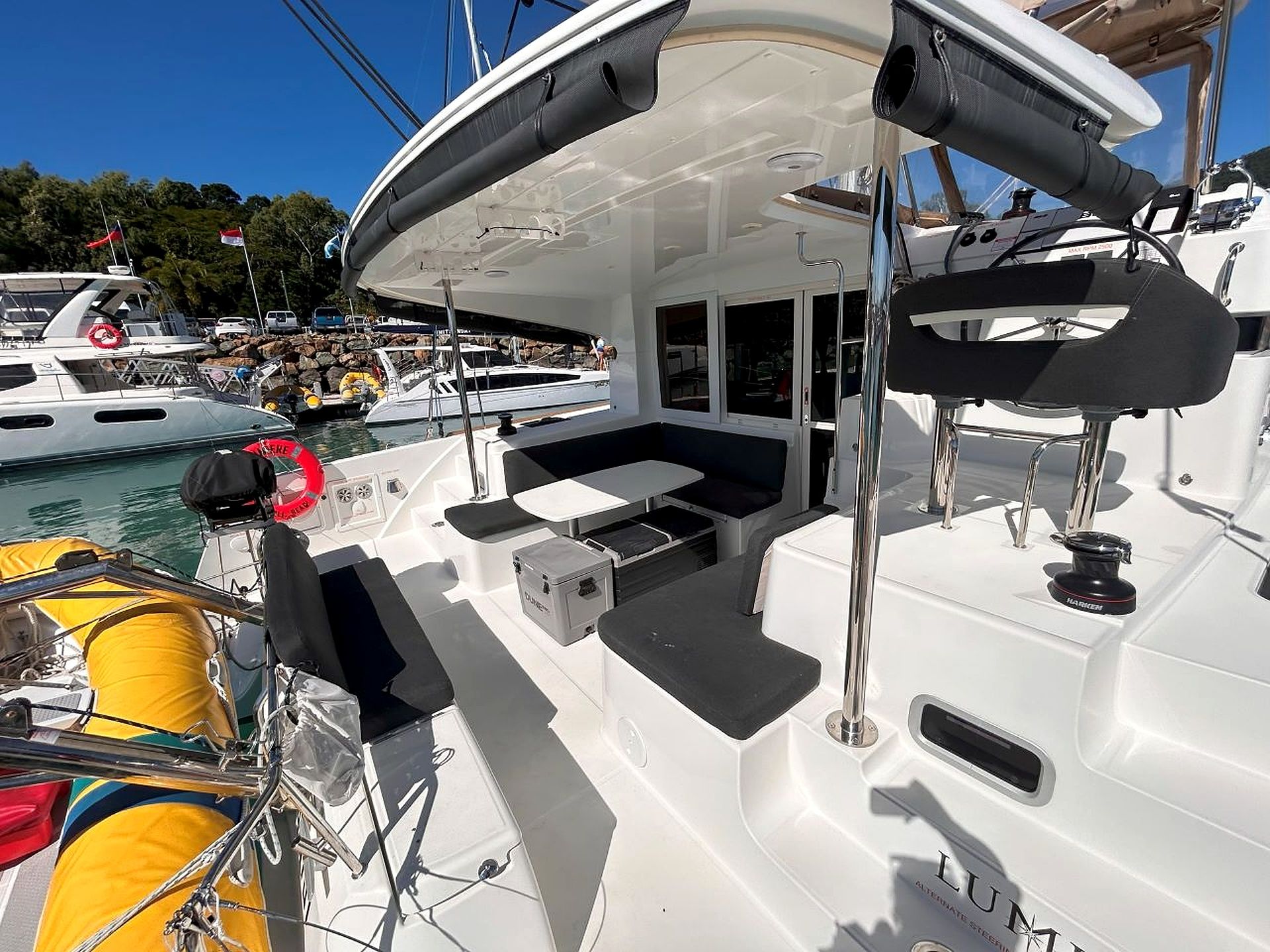 A boat's deck with seating, a small table, and a life preserver.