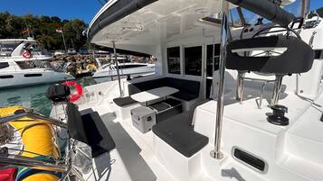A boat's deck with seating, a small table, and a life preserver.