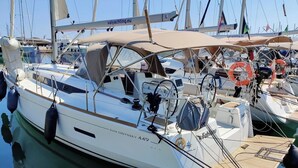 A sailboat docked at a marina with a covered deck area, a lifebuoy, and a name 'SUN ODYSSEY 449' visible. - Sun-Kissed Sailing Adventure in Zadar, Croatia (Bibinje)
