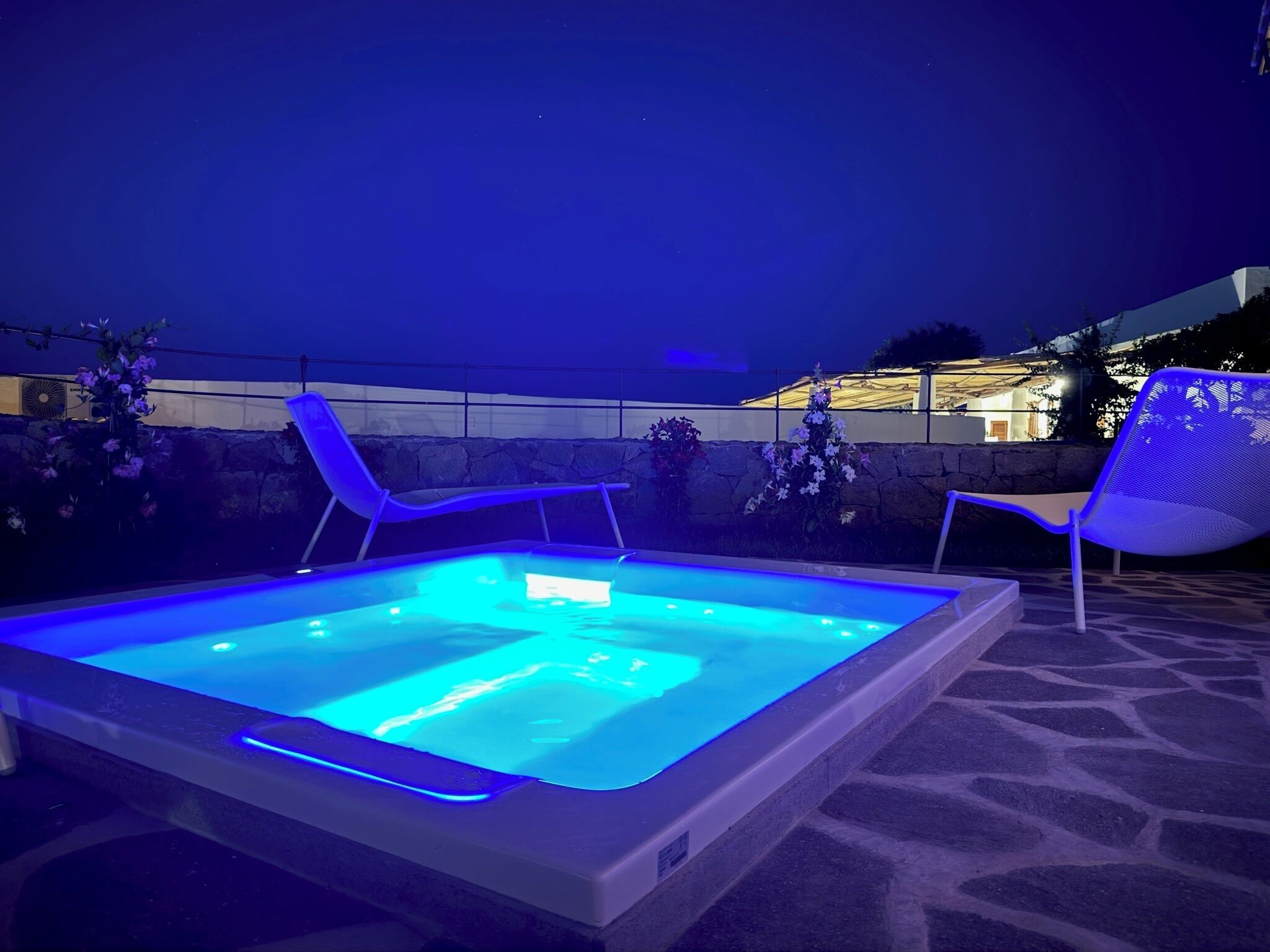 Un espace piscine extérieur chauffé, doté de chaises longues et d’une terrasse carrelée en pierre.