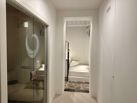Habitación de hotel con puerta de vidrio, cama, mesita pequeña y mesita de noche.
