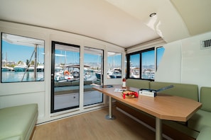 A modern interior with large windows, a wooden table, and a green couch. - Sun-Kissed Sailing Adventure in the Ionian Islands (Nikiana)