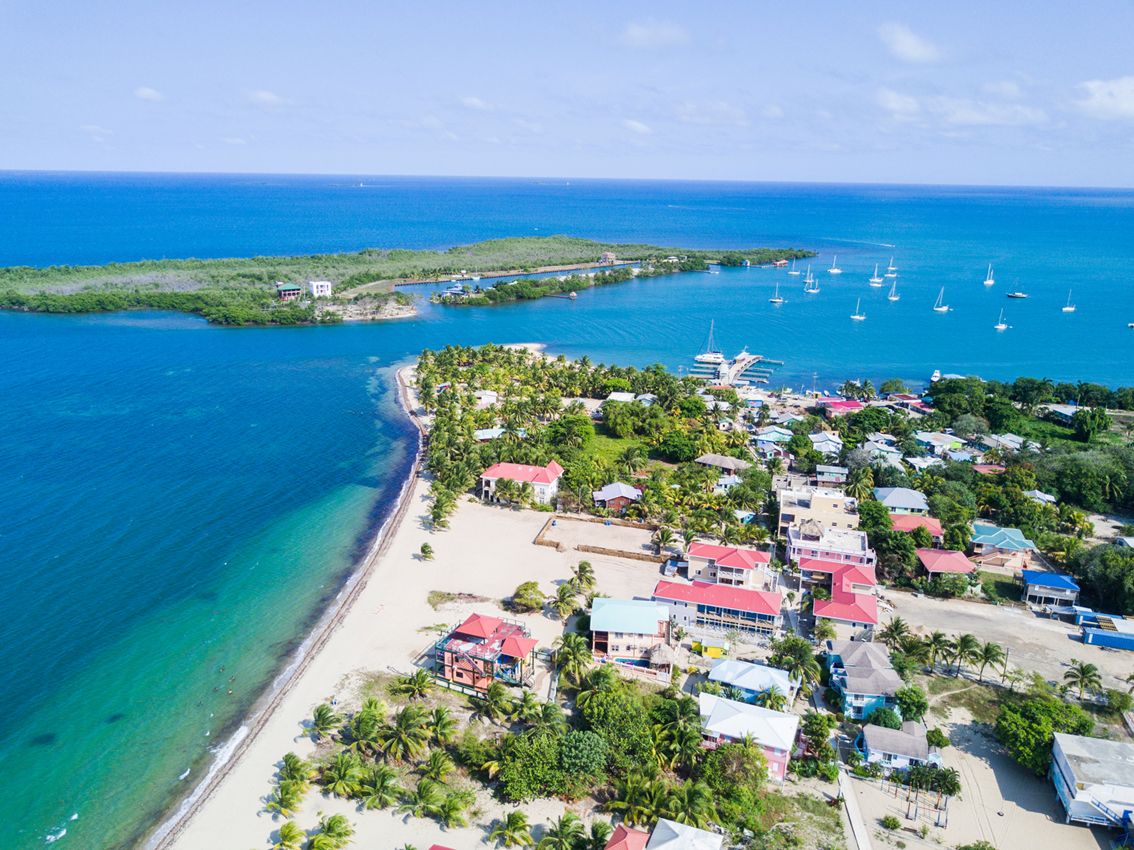 Une vue aérienne d’une ville côtière, avec ses bâtiments, sa plage et des bateaux sur l’eau.