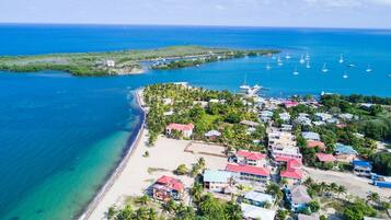 An aerial view of a coastal town with buildings, a beach, and boats in the water.