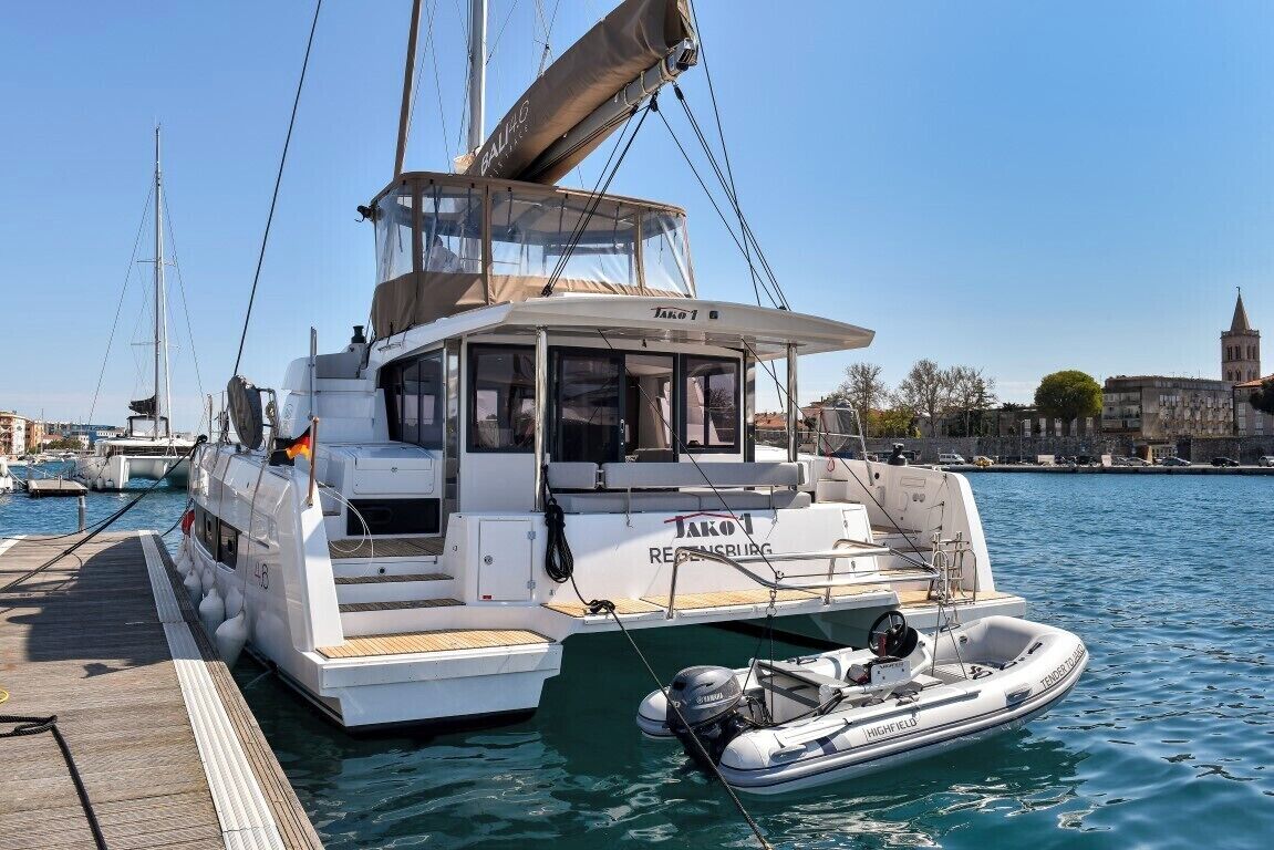 A white yacht docked at a marina with a clear view of the city skyline in the background.
