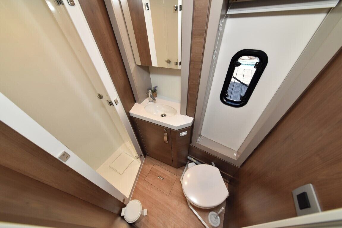A compact bathroom with a toilet, sink, and mirror.