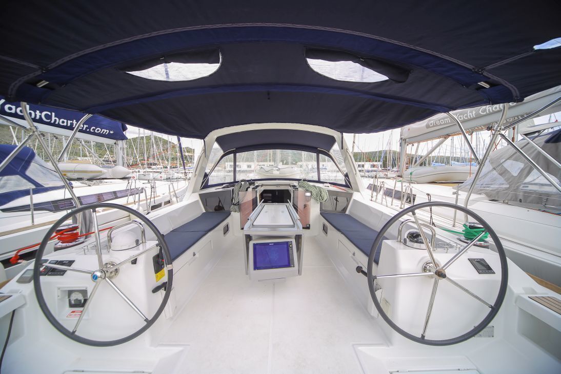 Convés de barco com volante, painel de controle e área de estar.