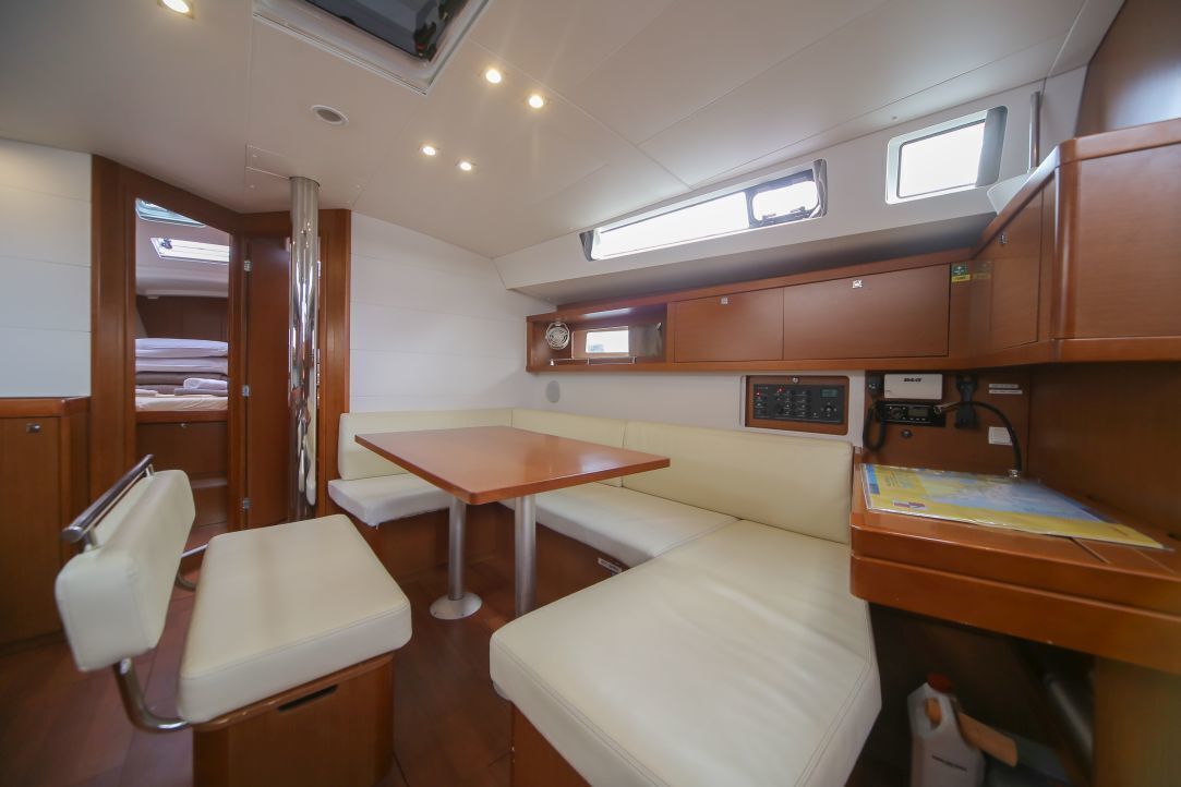 Un espacio interior compacto con cama, mesa, banco y una pequeña zona de kitchenette.