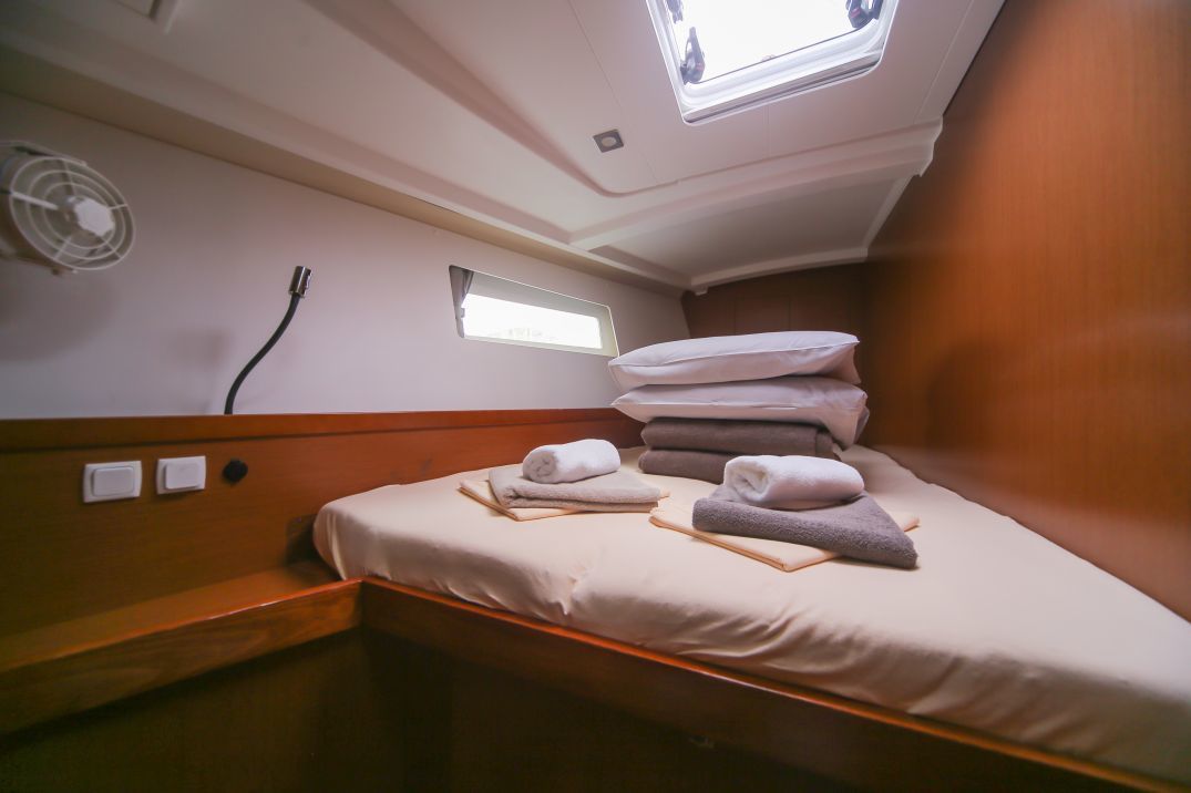 A compact room with a bed, a small window, and a wall-mounted fan.