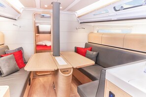 A compact interior with a wooden table, cushioned seating, and a small bed. - Sun-Kissed Sailing Adventure in Northern Croatia (Punat)