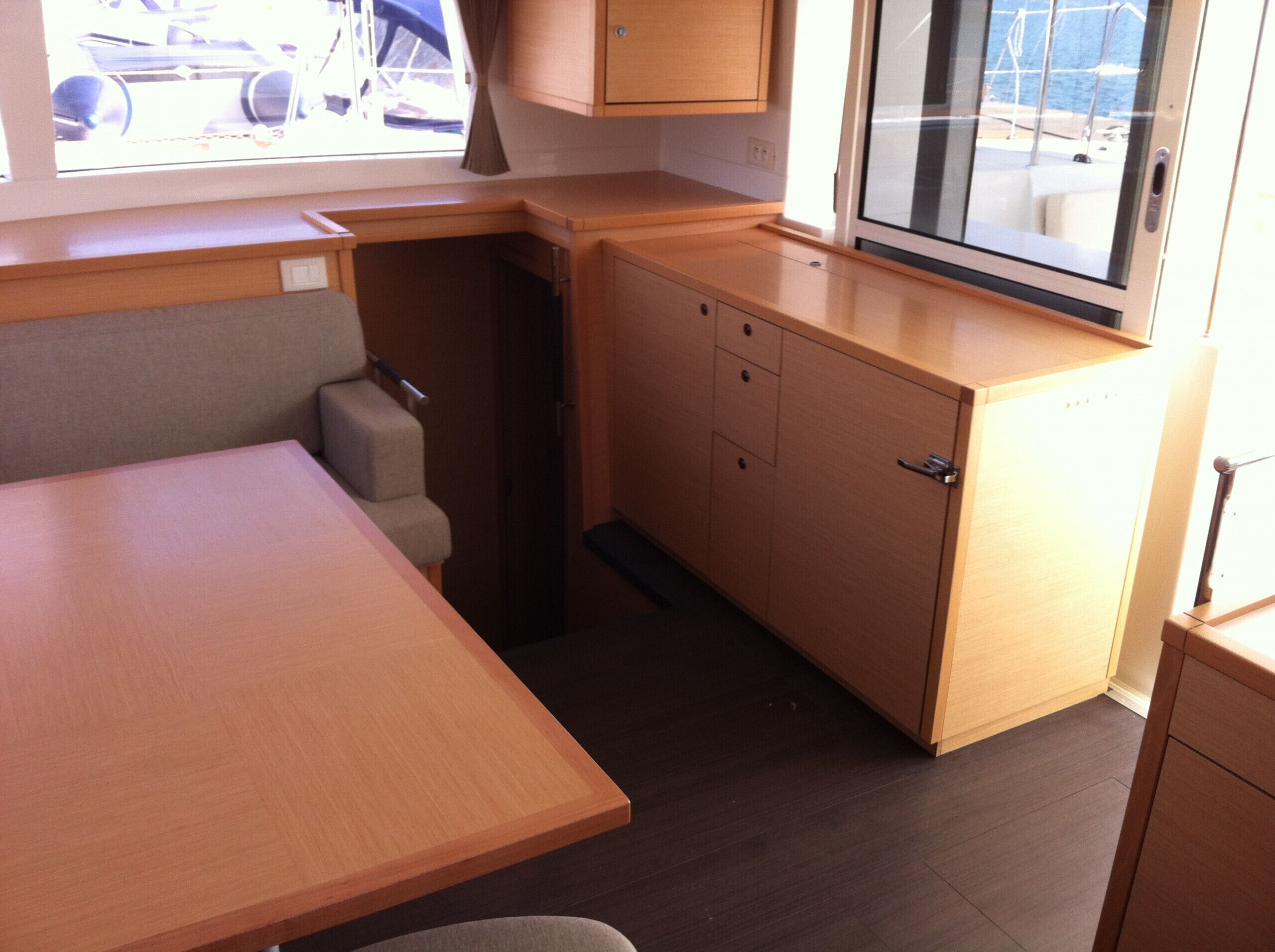 A compact kitchenette with a small table, a cabinet, and a window with a view of the sea.