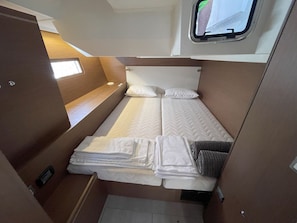 Ein kompaktes Schlafzimmer in einem Wohnmobil mit Etagenbett, kleinem Fenster und integriertem Stauraumschrank.