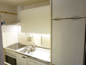 A kitchen with white cabinets, a stainless steel sink, and a built-in oven. - La Sarine 13 Studio, Dusche oder Bad, WC 2-Bettwohnung by Interhome (Gstaad)