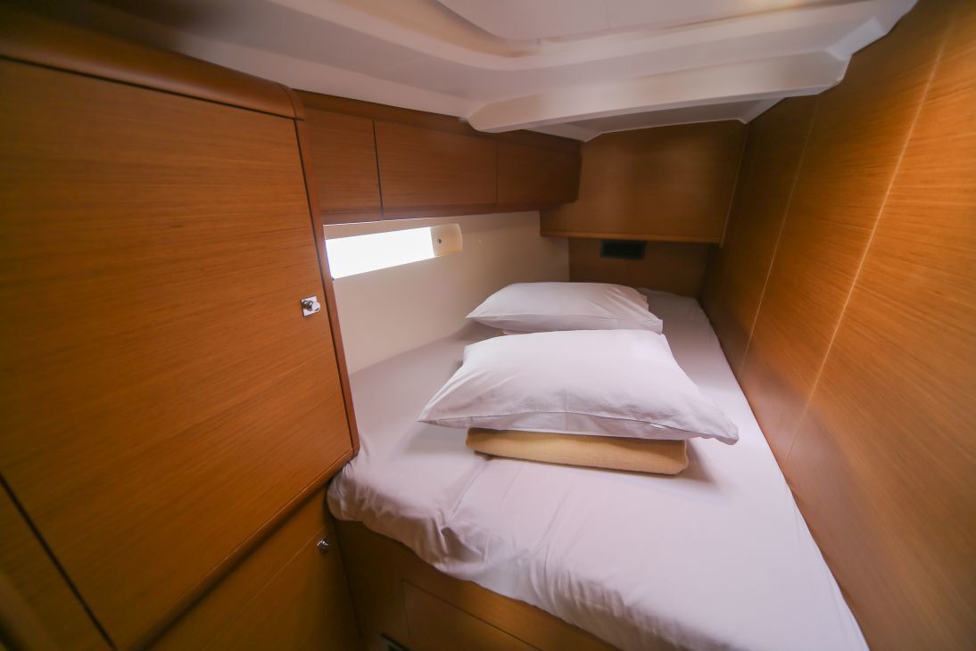 A compact cabin with a single bed, wooden cabinetry, and a small window.