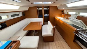 Um espaço interior compacto com mesa central, assentos, cozinha compacta e iluminação embutida.