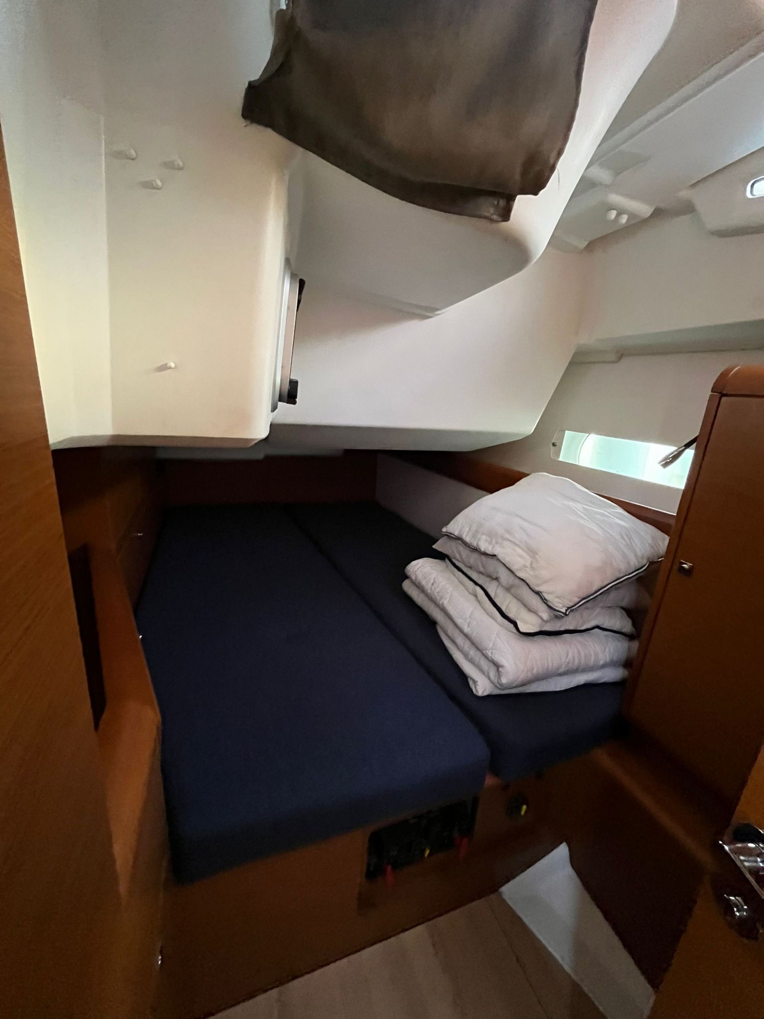 A compact RV interior with a bunk bed, a small kitchenette, and a window for natural light.