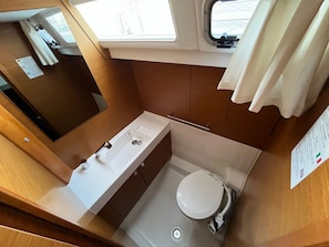 A compact bathroom with a sink, toilet, and shower. - Sun-Kissed Sailing Adventure in Zadar, Croatia (Bibinje)