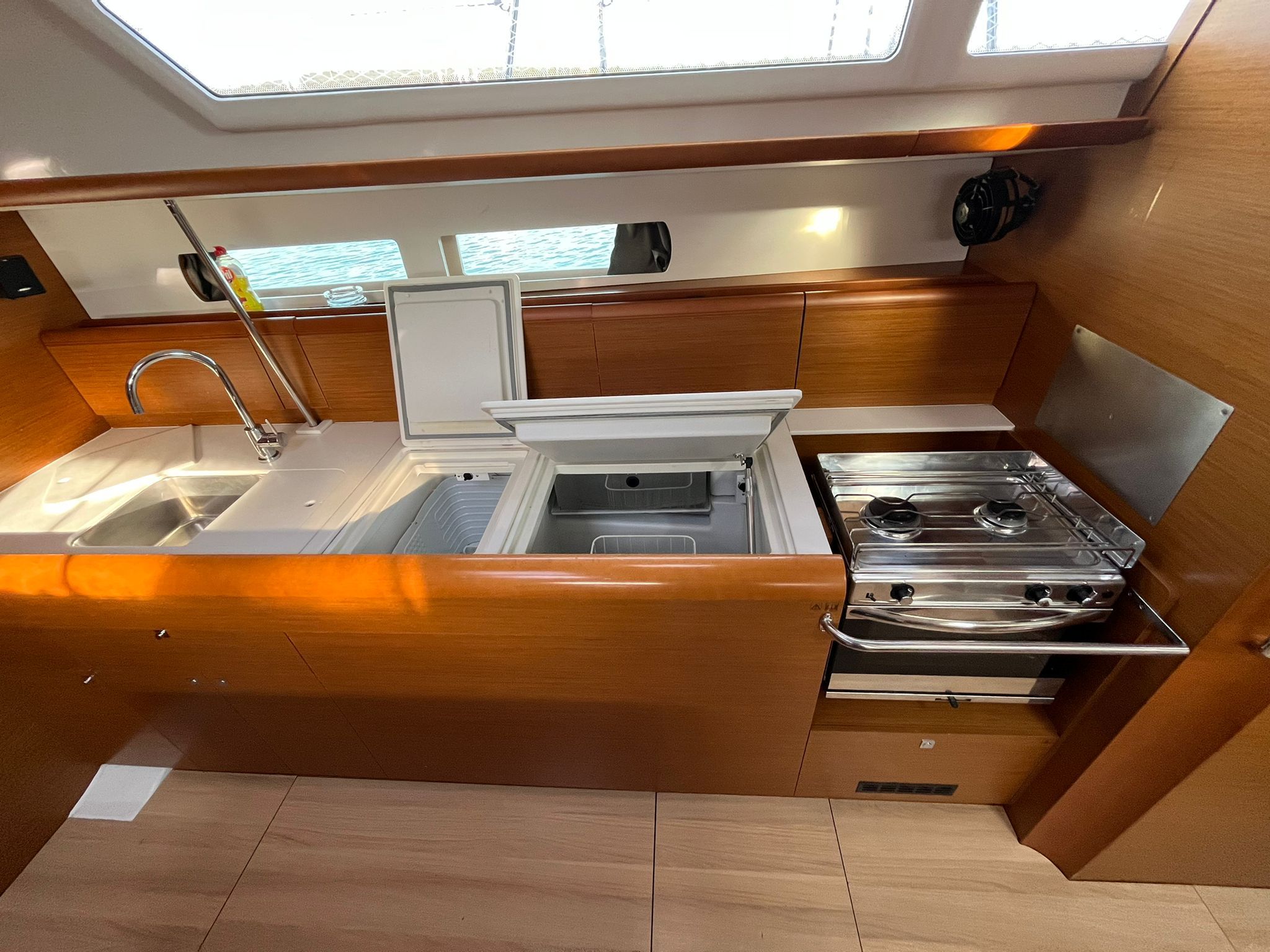A compact galley with a sink, stove, and storage drawers.