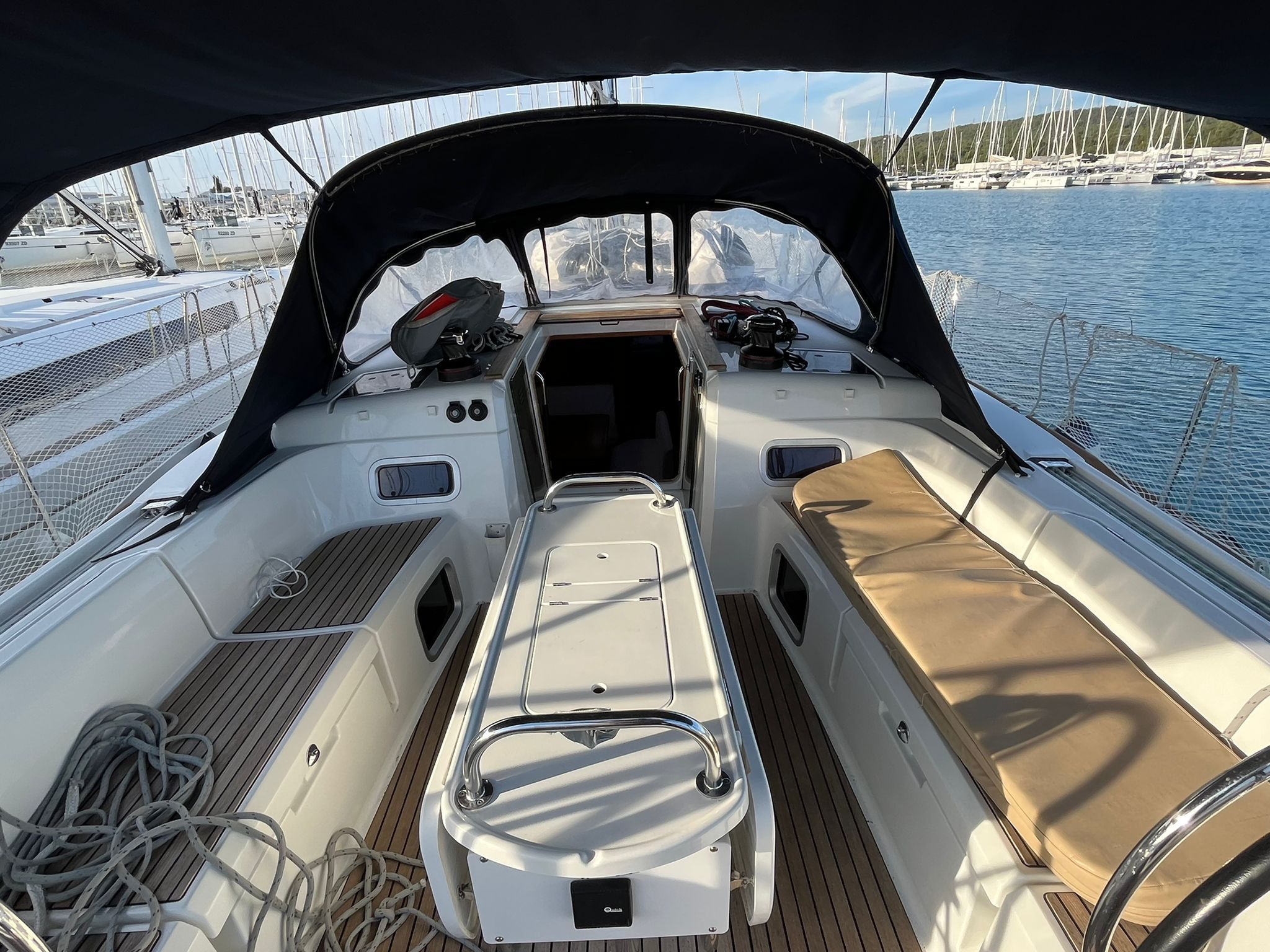 A boat's deck with a steering wheel, control panel, and seating area.