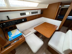 Un intérieur de bateau compact comprenant un panneau de commande, un espace salon avec des sièges rembourrés et une petite table.