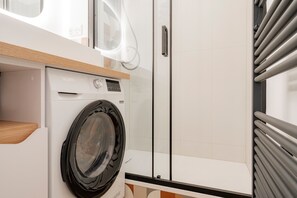 A modern laundry area with a Valberg washing machine, a wooden countertop, and a glass door. - Les Cimes d'Hestia - Proche station de ski (La Salle-les-Alpes)