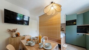 Una cucina moderna con forno integrato, un'area pranzo con tavolo e sedie in legno e un televisore montato a parete.