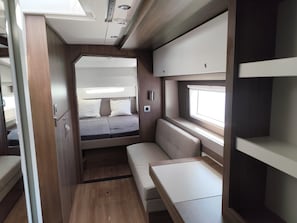 A compact RV interior with a bed, seating area, and storage compartments. - Sun-Kissed Sailing Adventure in Provence-Alpes-Côte d'Azur (Hyères)