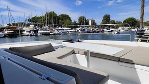 A marina with boats docked, a lounge area with cushions, and a clear view of the water. - Sun-Kissed Sailing Adventure in Provence-Alpes-Côte d'Azur (Hyères)