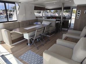 A modern interior with a dining area, seating, and a view of the marina. - Sun-Kissed Sailing Adventure in Provence-Alpes-Côte d'Azur (Hyères)