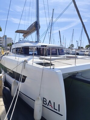 A white yacht named 'BALI' docked at a marina with other boats, clear skies, and buildings in the background. - Sun-Kissed Sailing Adventure in Provence-Alpes-Côte d'Azur (Hyères)