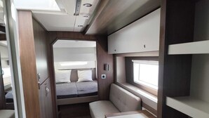 A compact RV interior with a bed, seating area, and storage compartments. - Sun-Kissed Sailing Adventure in Provence-Alpes-Côte d'Azur (Hyères)