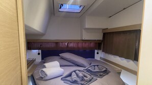 Una cama litera con tragaluz, una mesita de noche y un cabecero.