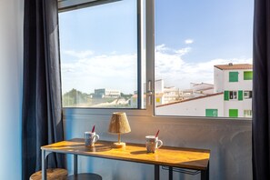 Ein Zimmer mit Fenster, einem Tisch mit zwei Tassen und einer Lampe.