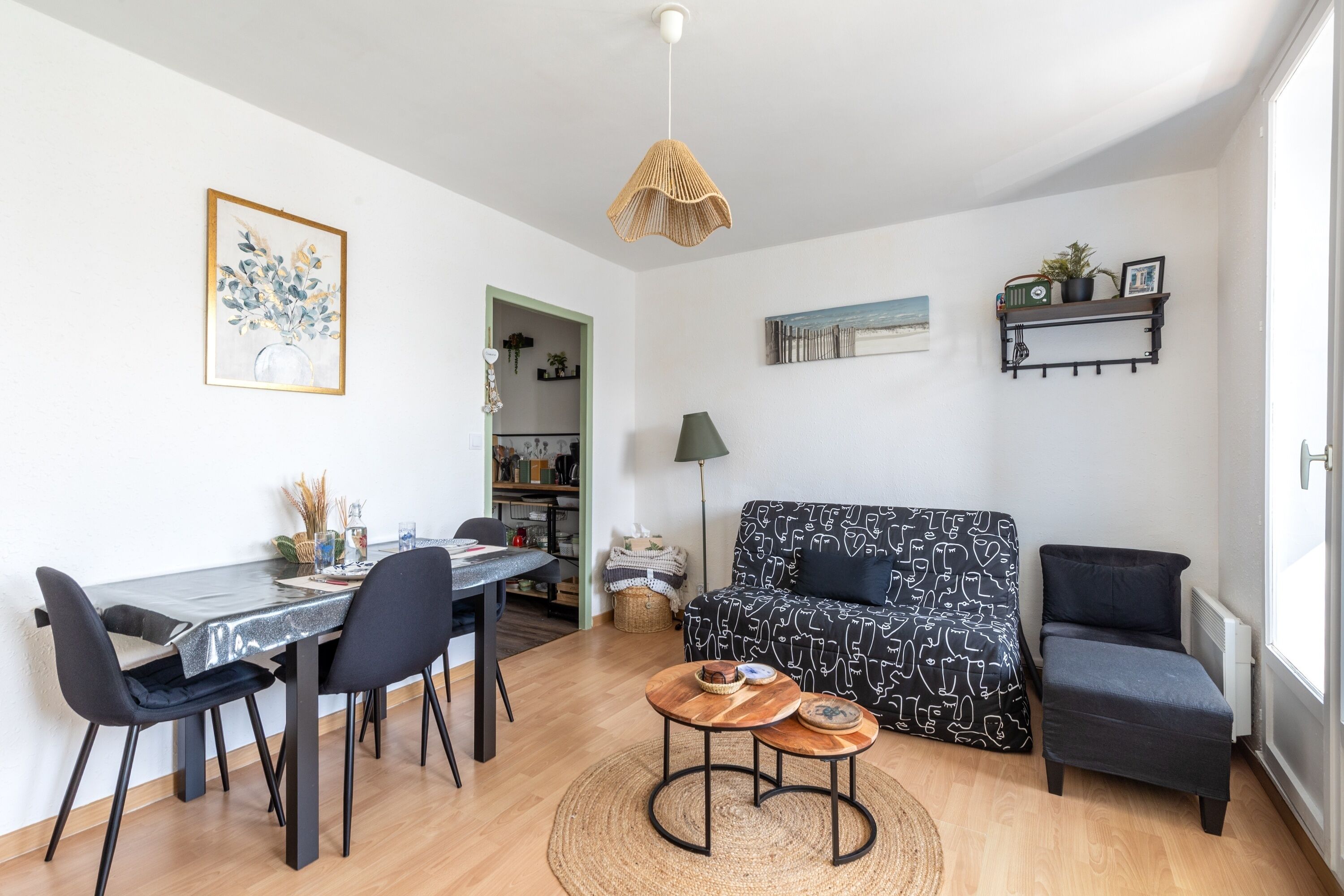 A modern living room with a dining table, chairs, a sofa, a small coffee table, and a hanging light fixture.