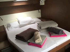 A neatly made bed with pillows and folded towels in various colors.
