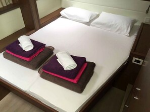 A double bed with white linens and two towels folded on each side.