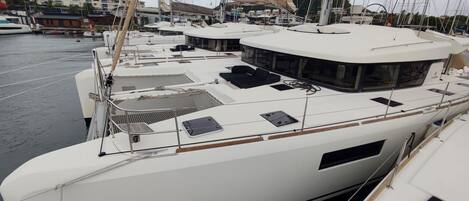 A marina with multiple yachts docked, featuring open deck areas and seating arrangements.