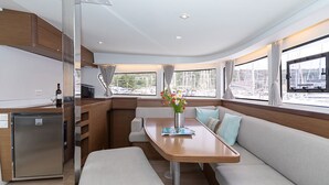 Cozinha compacta com geladeira, área de refeições com mesa e bancos, e janelas amplas com vista para o calhavete.