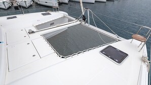 Convés de barco com área de estar, uma pequena janela e uma grade de metal.