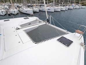 Ein Bootsdeck mit Sitzgelegenheit, einem kleinen Fenster und einem Metallgitter.