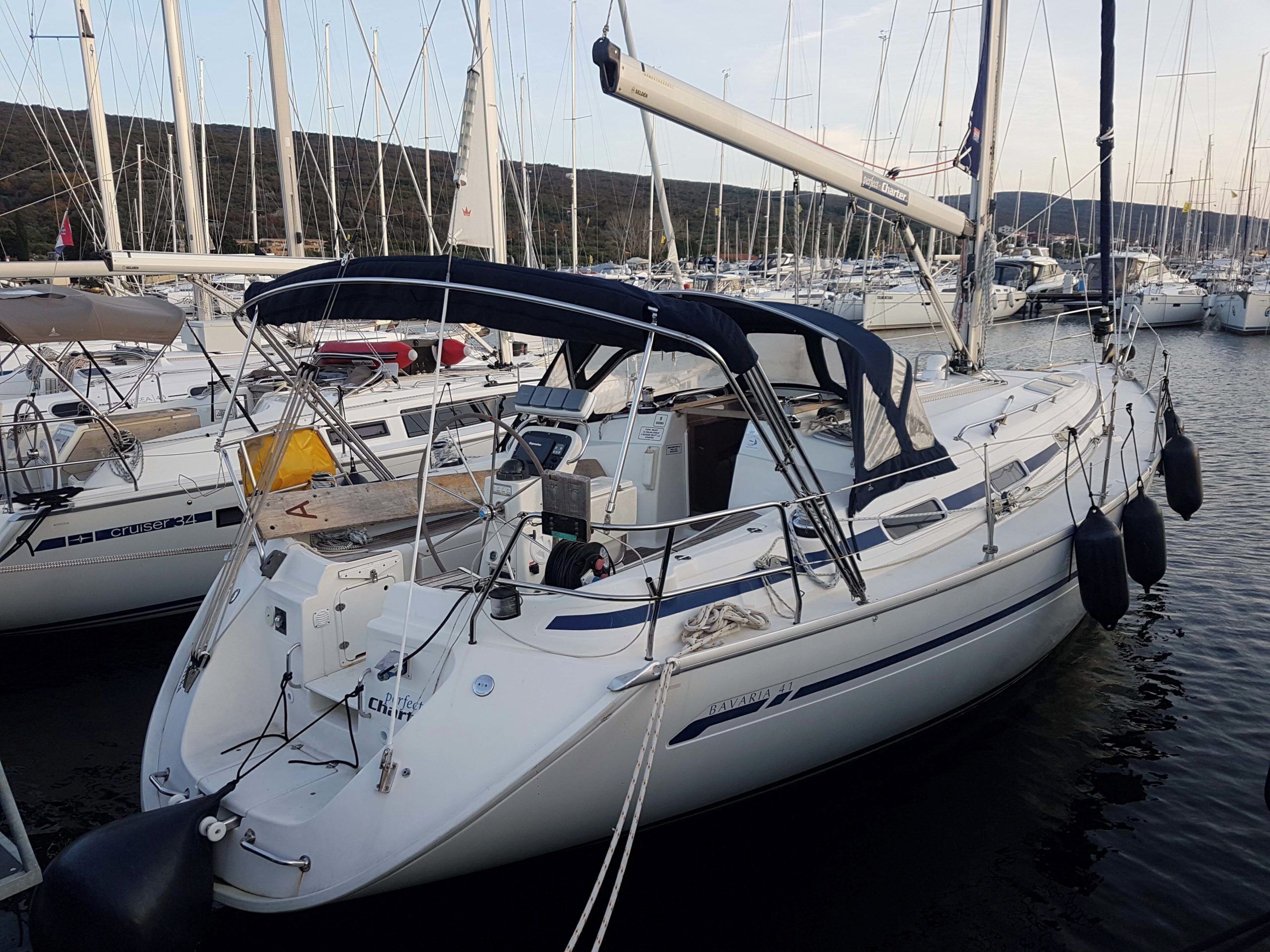 A marina with several sailboats docked, featuring a cabin with a canopy, a steering wheel, and various navigational equipment.