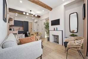 A modern living room with a sofa, a dining area, a kitchen, and a fireplace. - L'Atelier des Remparts - Au cœur du Vieil Antibes (Antibes)