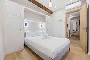 A modern bedroom with a bed, built-in wardrobe, and a wooden ceiling beam. - L'Atelier des Remparts - Au cœur du Vieil Antibes (Antibes)